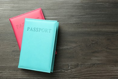 Photo of Passports in color covers on wooden table, top view. Space for text