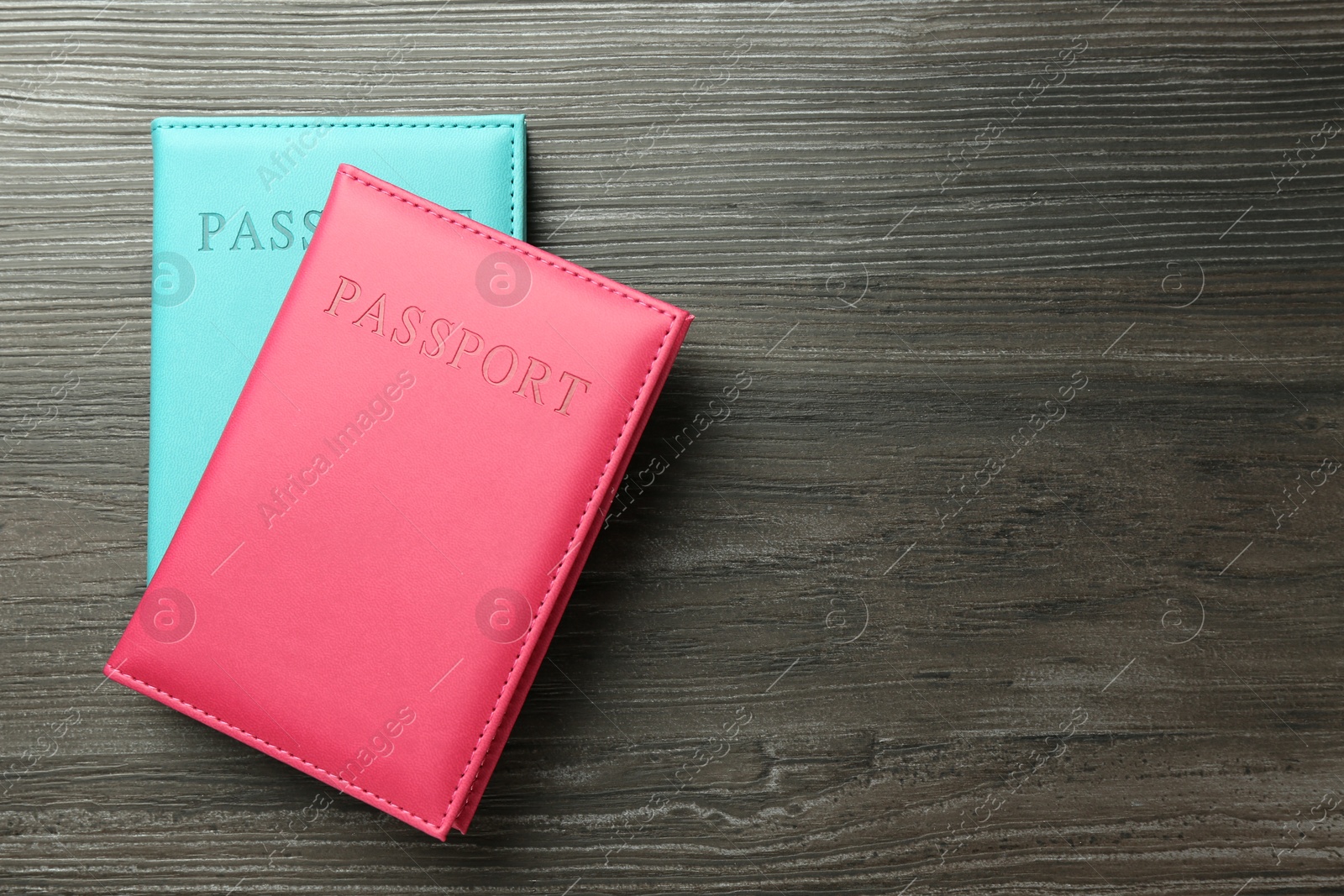 Photo of Passports in color covers on wooden table, top view. Space for text