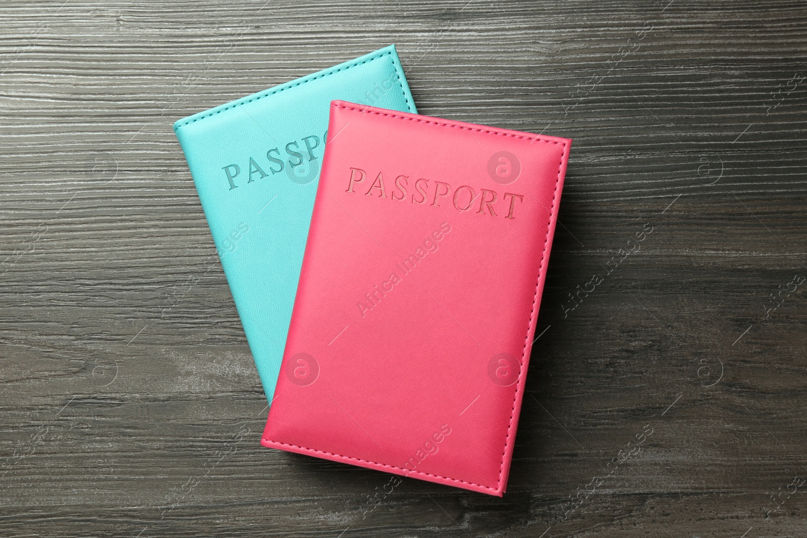 Photo of Passports in color covers on wooden table, top view