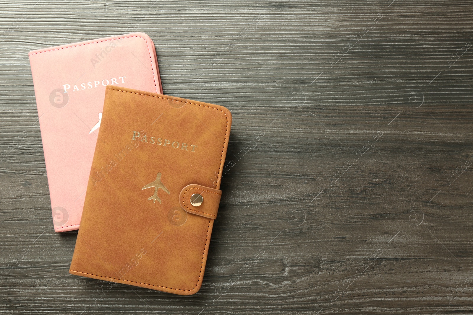 Photo of Passports in color covers on wooden table, top view. Space for text