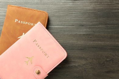 Photo of Passports in color covers on wooden table, top view. Space for text