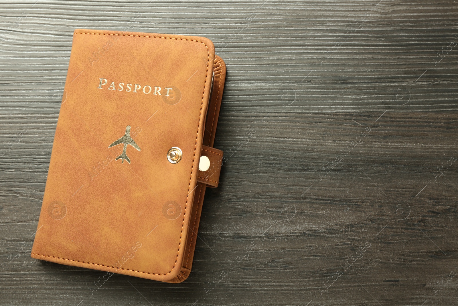 Photo of Passport in brown cover on wooden table, top view. Space for text