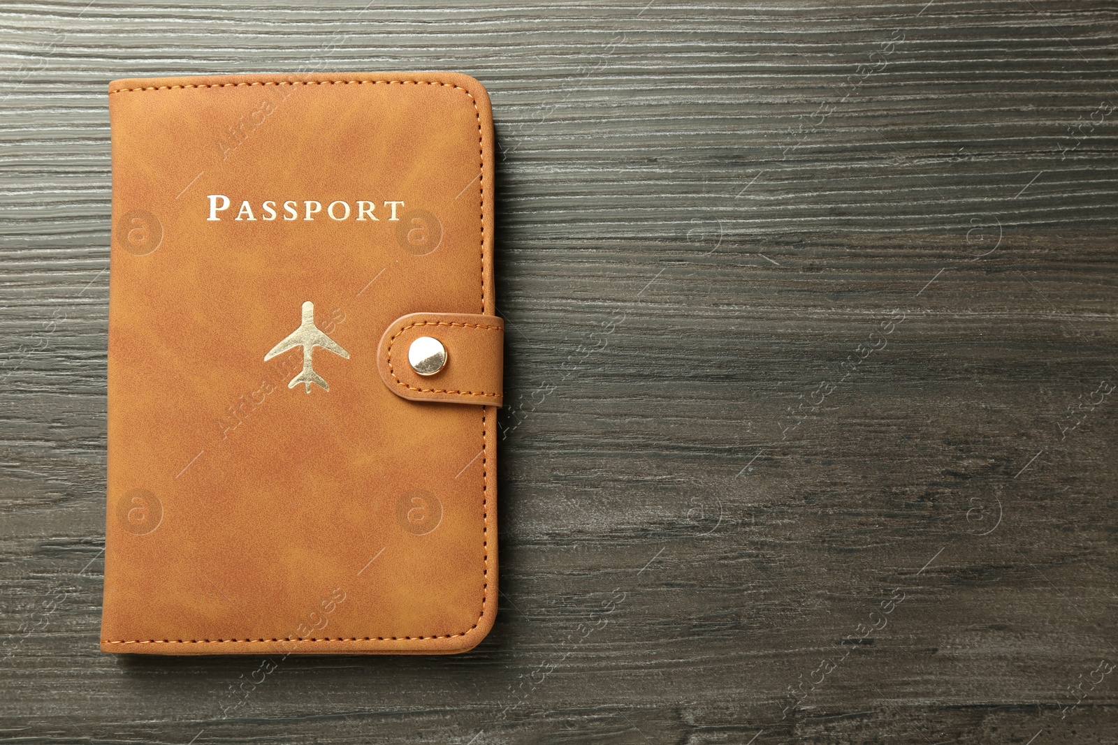 Photo of Passport in brown cover on wooden table, top view. Space for text