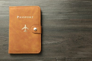 Photo of Passport in brown cover on wooden table, top view. Space for text