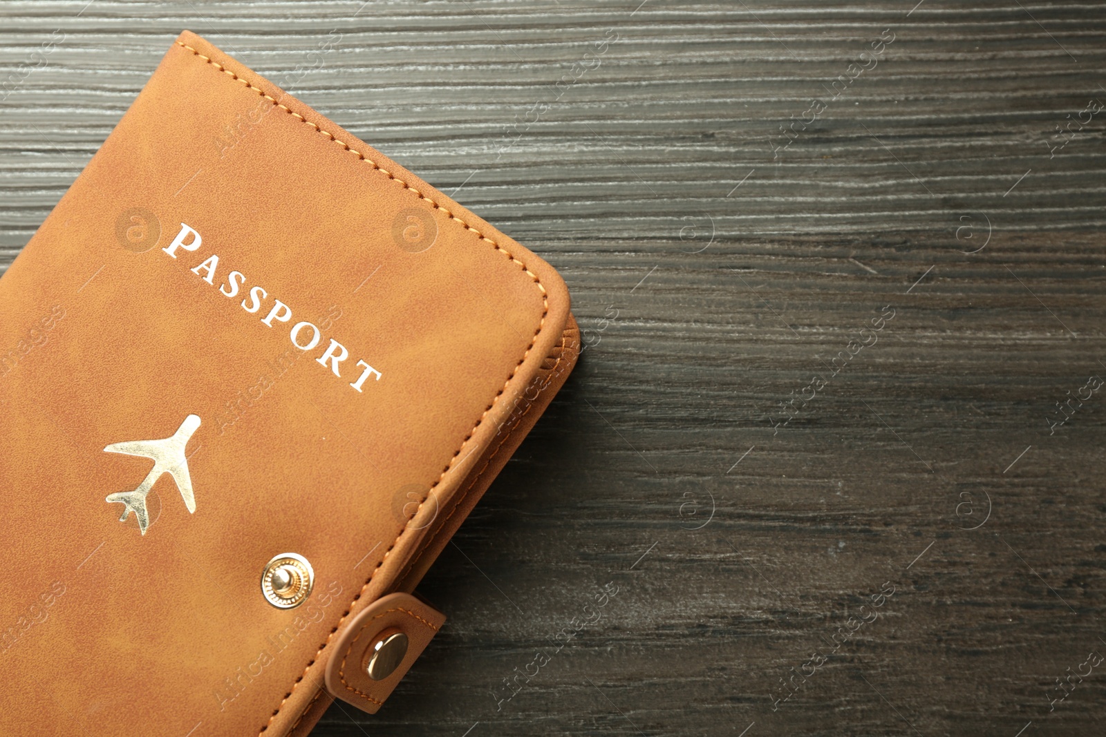 Photo of Passport in brown cover on wooden table, top view. Space for text