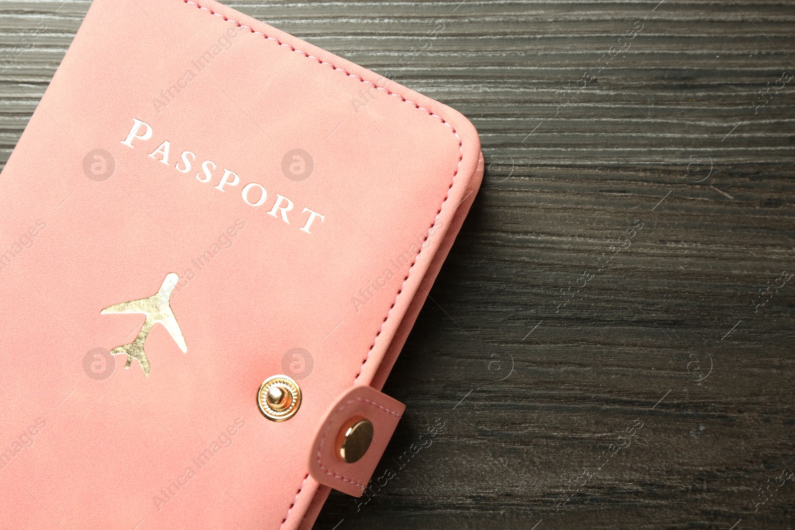 Photo of Passport in pink cover on wooden table, top view. Space for text