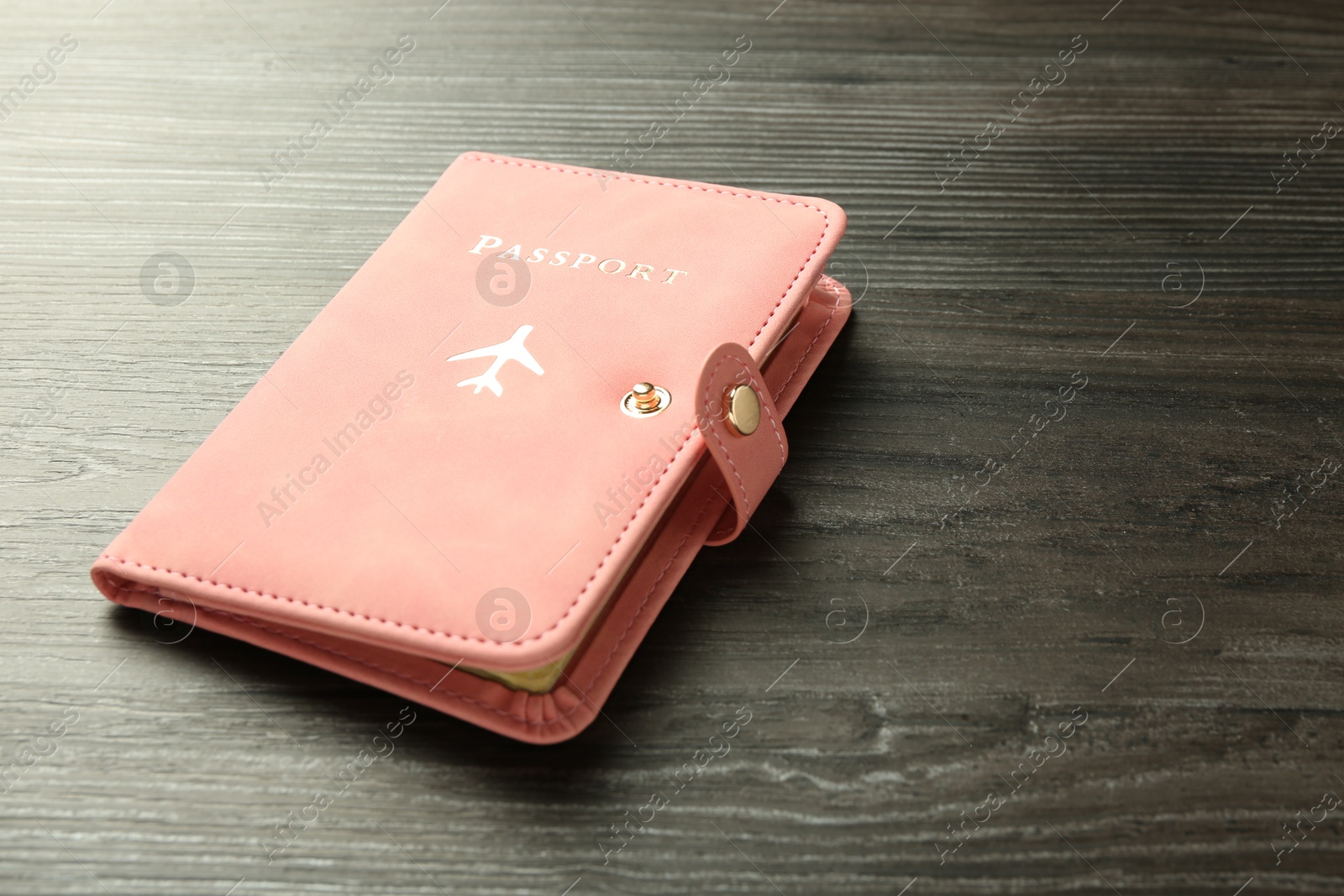 Photo of Passport in pink cover on wooden table