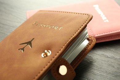 Photo of Passports in color covers on wooden table, closeup