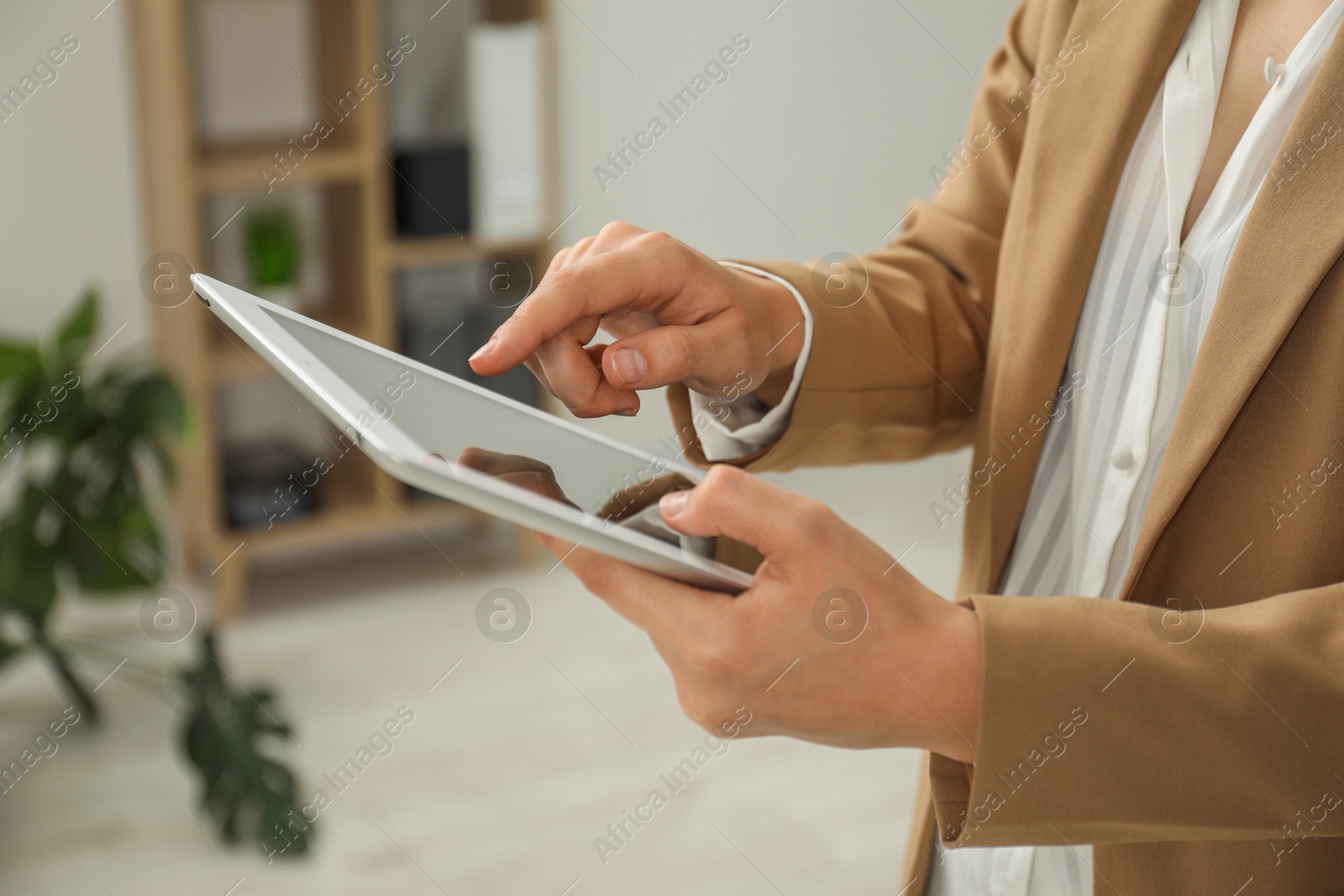 Photo of Businesswoman using tablet indoors, closeup. Modern technology