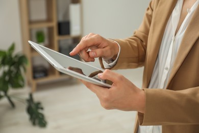 Photo of Businesswoman using tablet indoors, closeup. Modern technology