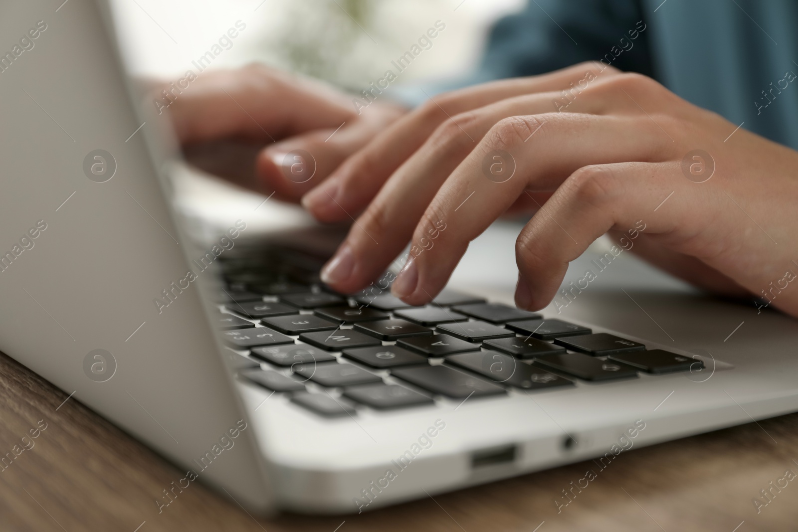 Photo of Businesswoman using laptop at wooden table indoors, closeup. Modern technology