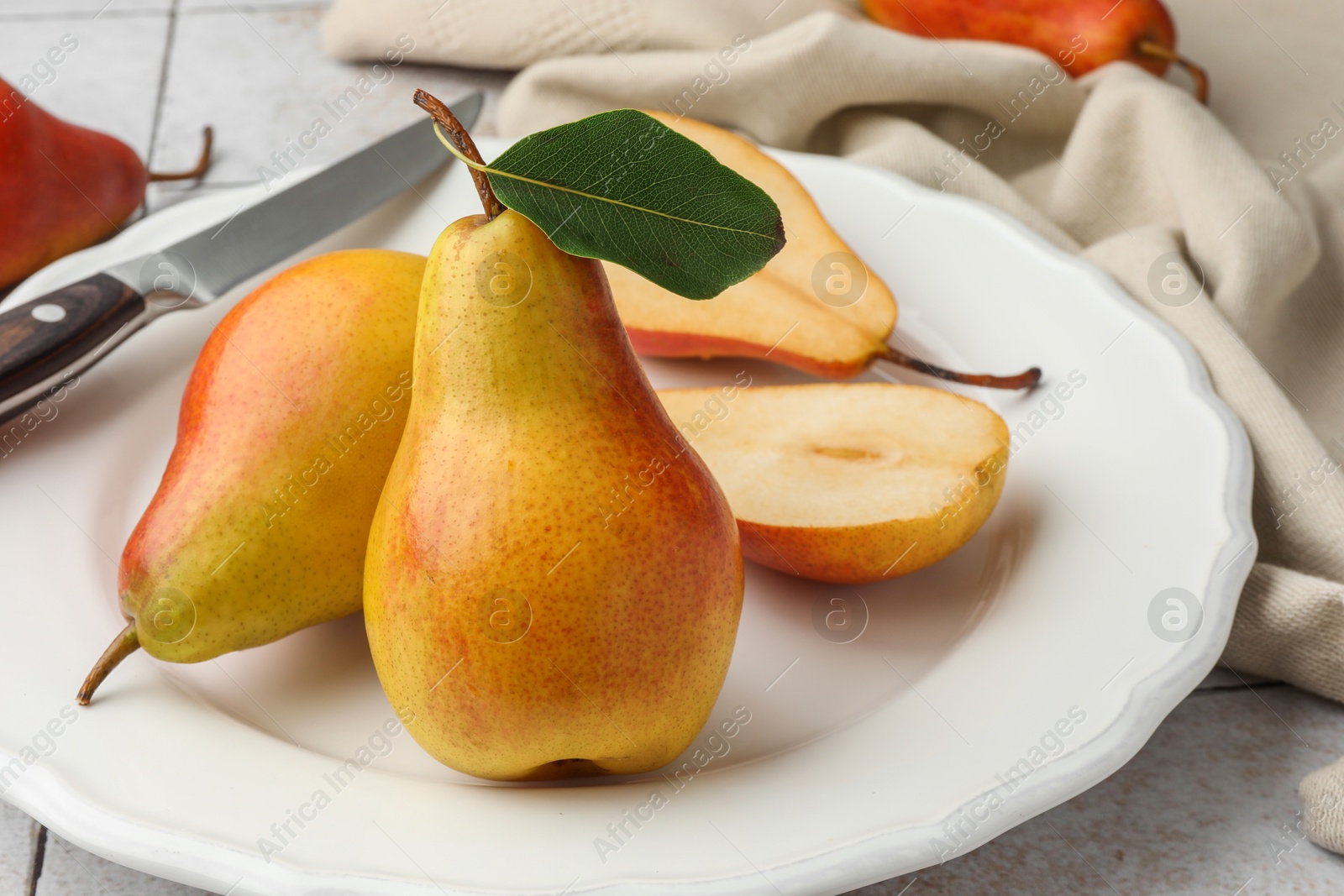 Photo of Ripe juicy pears on light tiled table, closeup