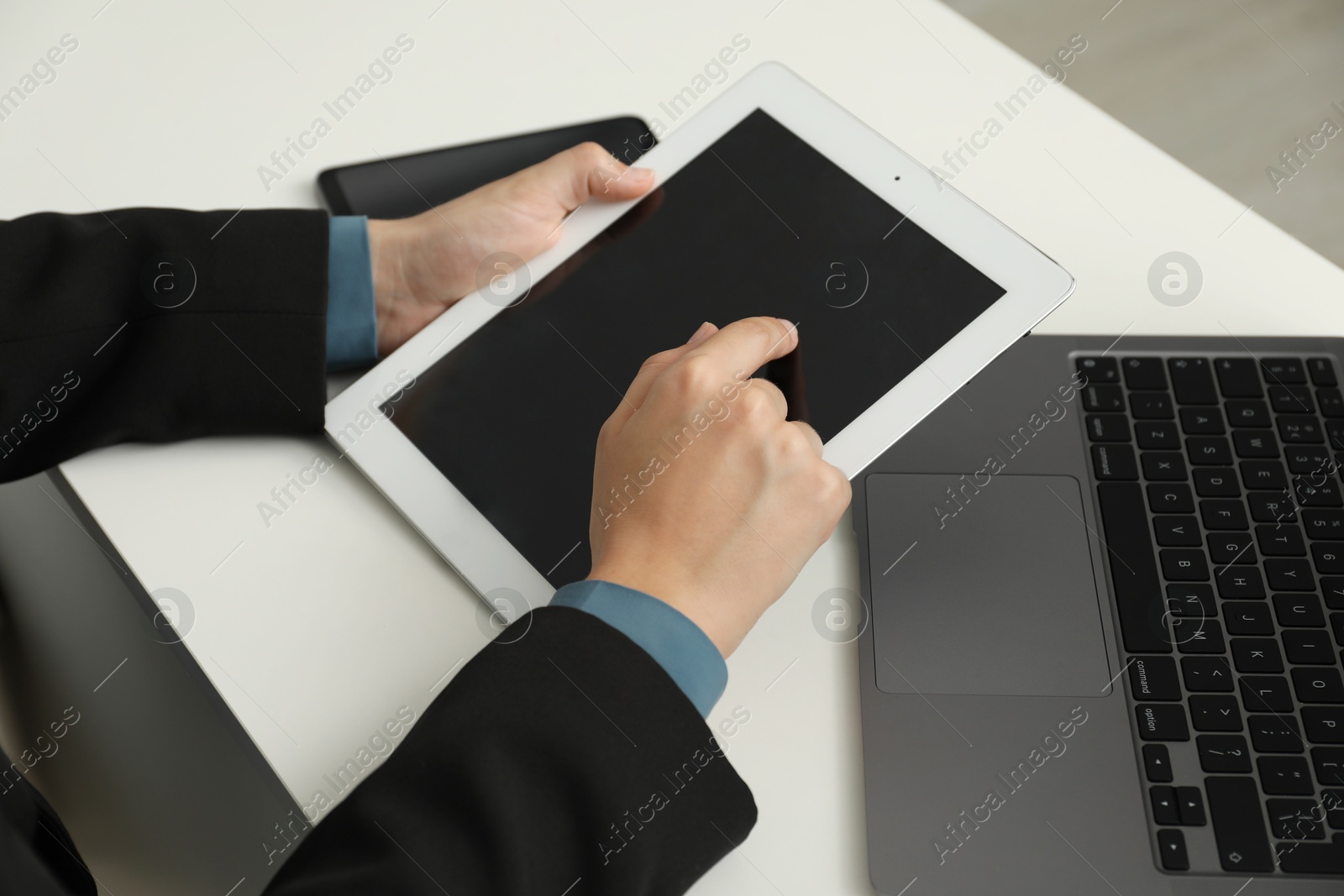 Photo of Businesswoman using tablet at white table indoors, closeup. Modern technology