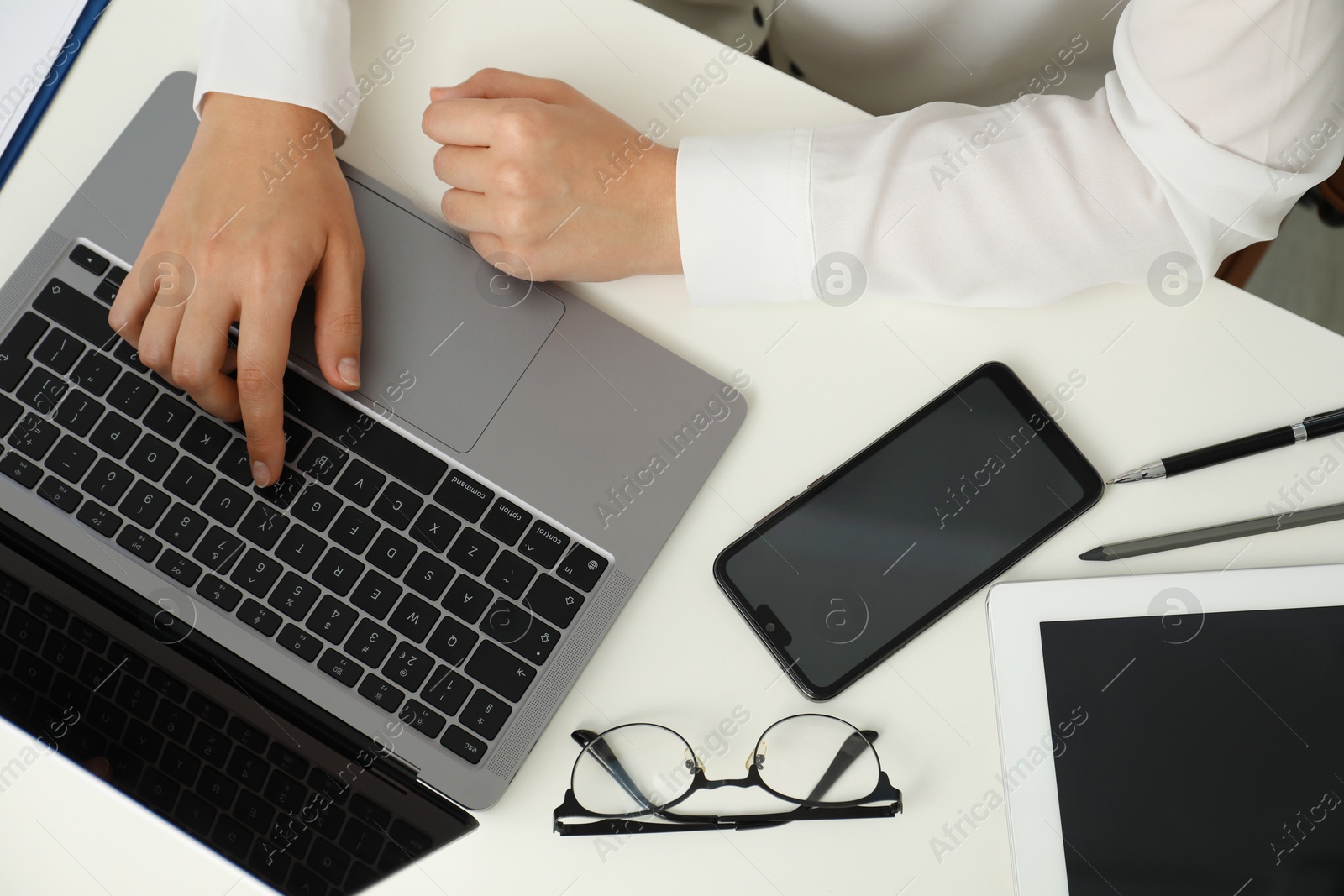 Photo of Businesswoman using laptop at white table indoors, top view. Modern technology