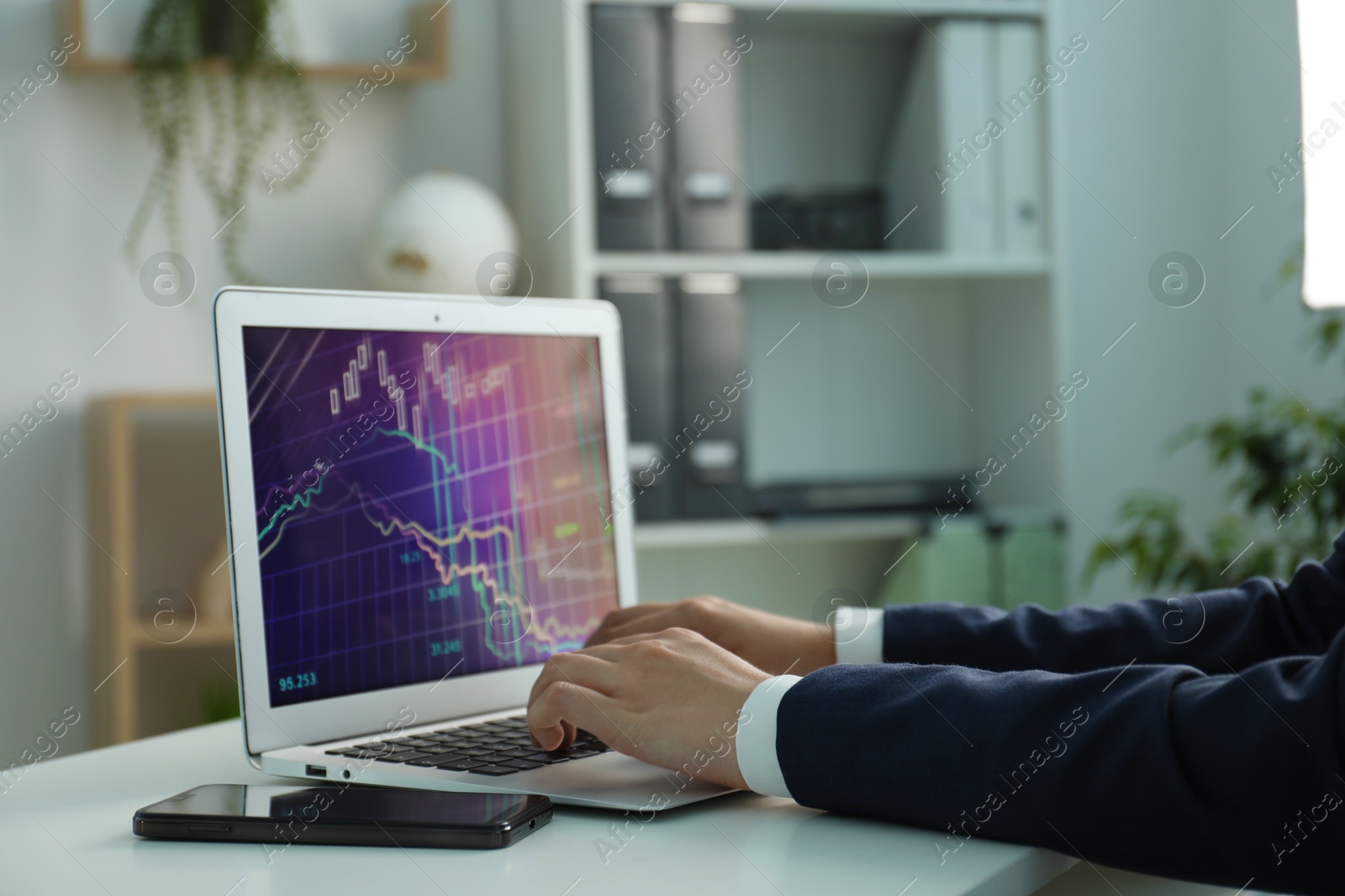 Photo of Businesswoman using laptop at white table indoors, closeup. Modern technology