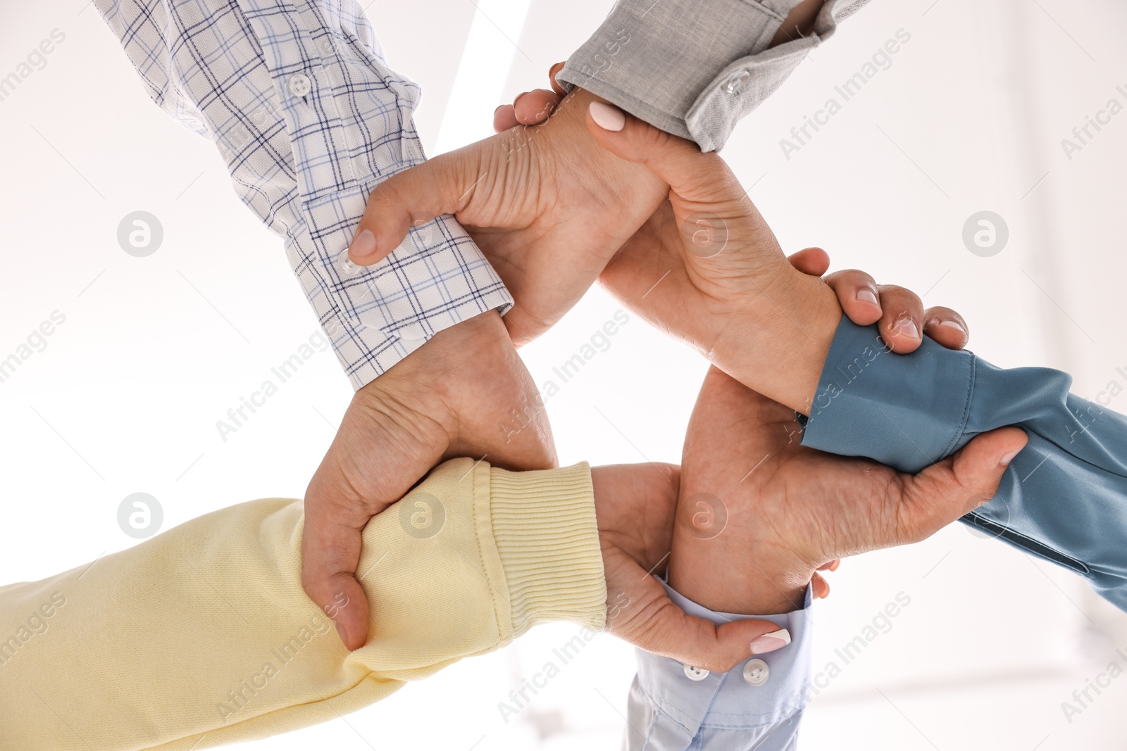 Photo of Teamwork. Group of employees joining hands in office, bottom view