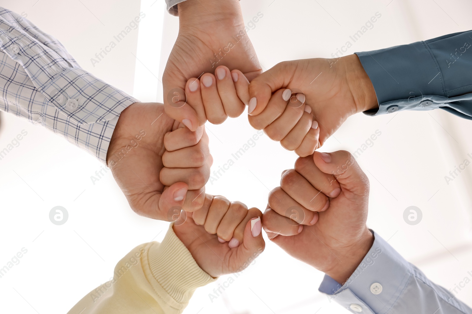 Photo of Teamwork. Group of employees joining hands in office, bottom view