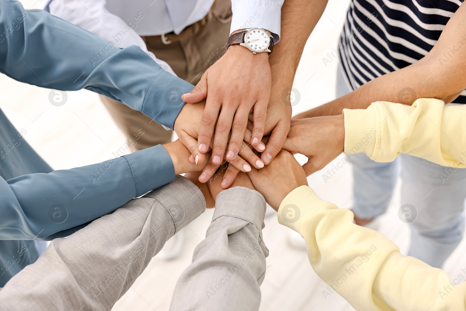 Photo of Teamwork. Group of employees joining hands in office, closeup