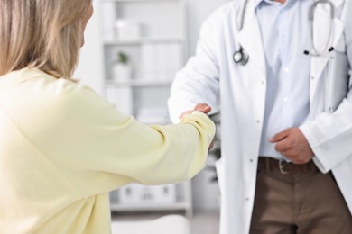 Photo of Healthcare worker shaking hands with patient in hospital, closeup