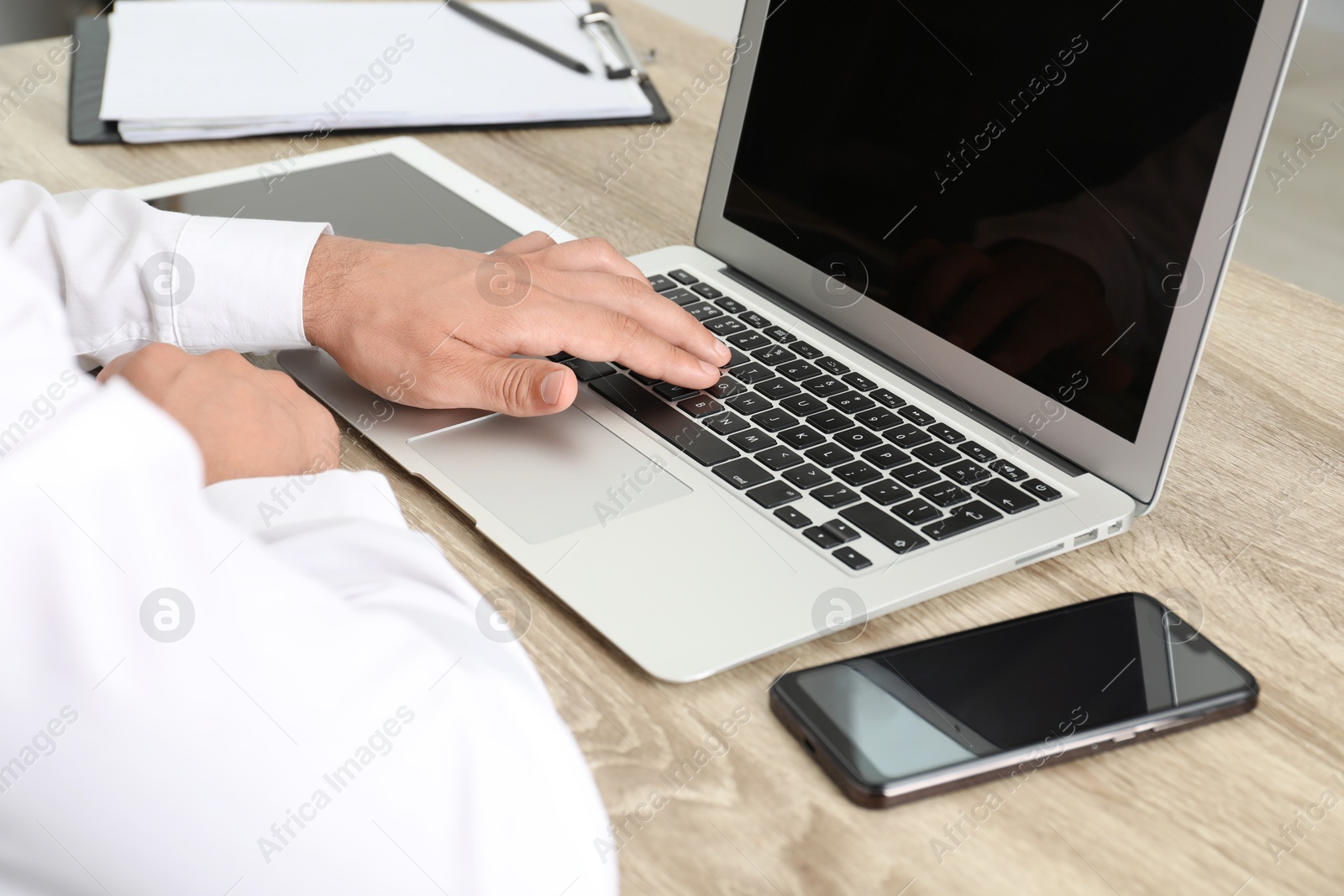 Photo of Businessman using laptop at wooden table, closeup. Modern technology