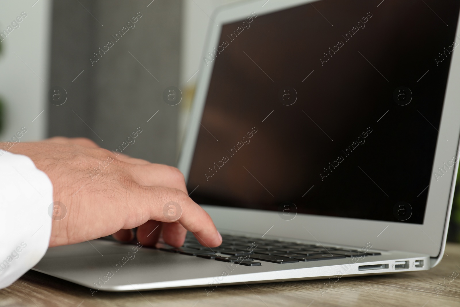 Photo of Businessman using laptop at wooden table, closeup. Modern technology