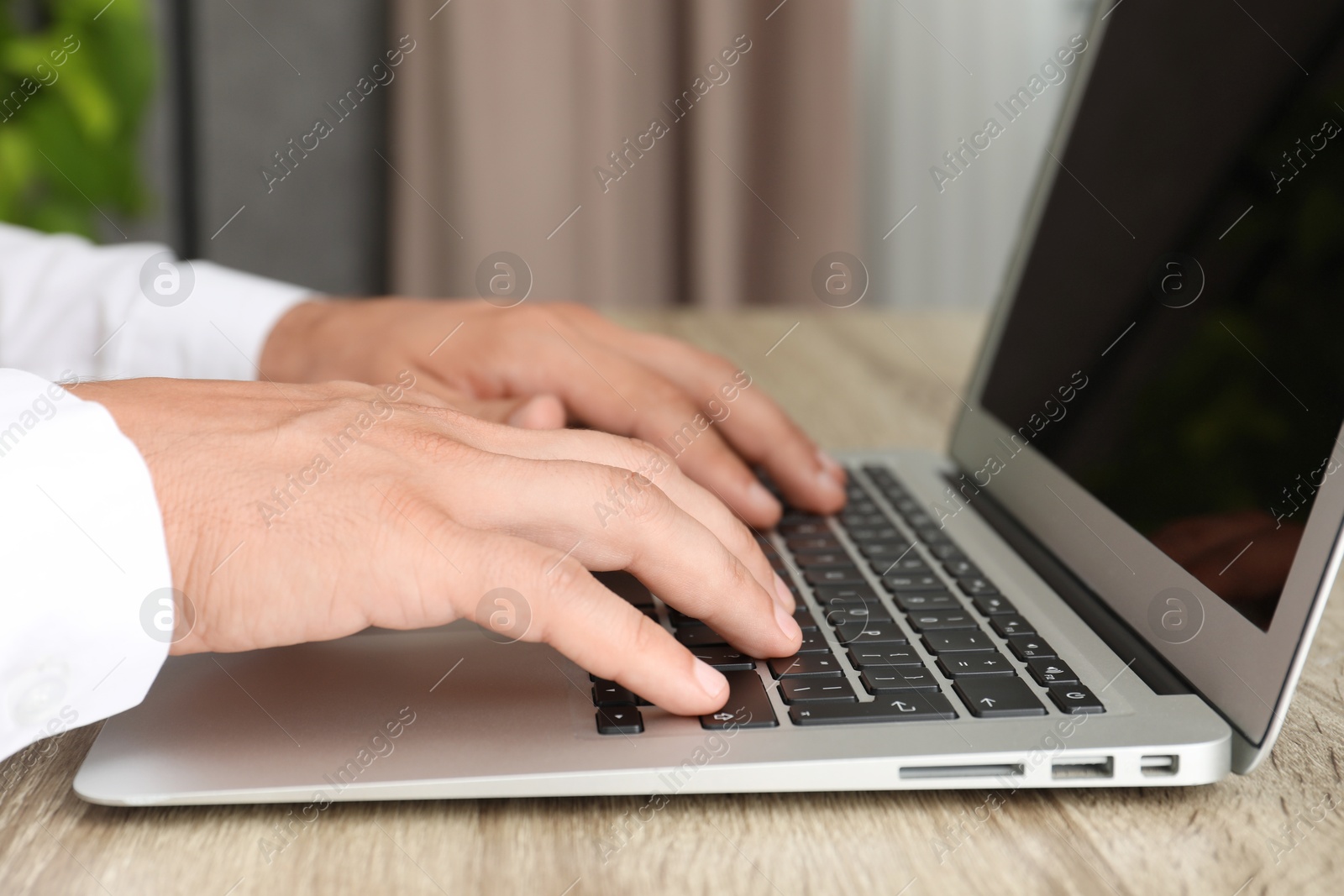 Photo of Businessman using laptop at wooden table, closeup. Modern technology