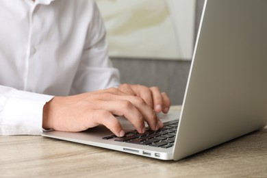 Photo of Businessman using laptop at wooden table, closeup. Modern technology