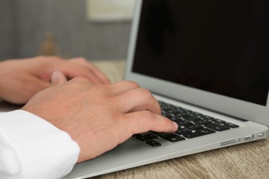 Photo of Businessman using laptop at wooden table, closeup. Modern technology