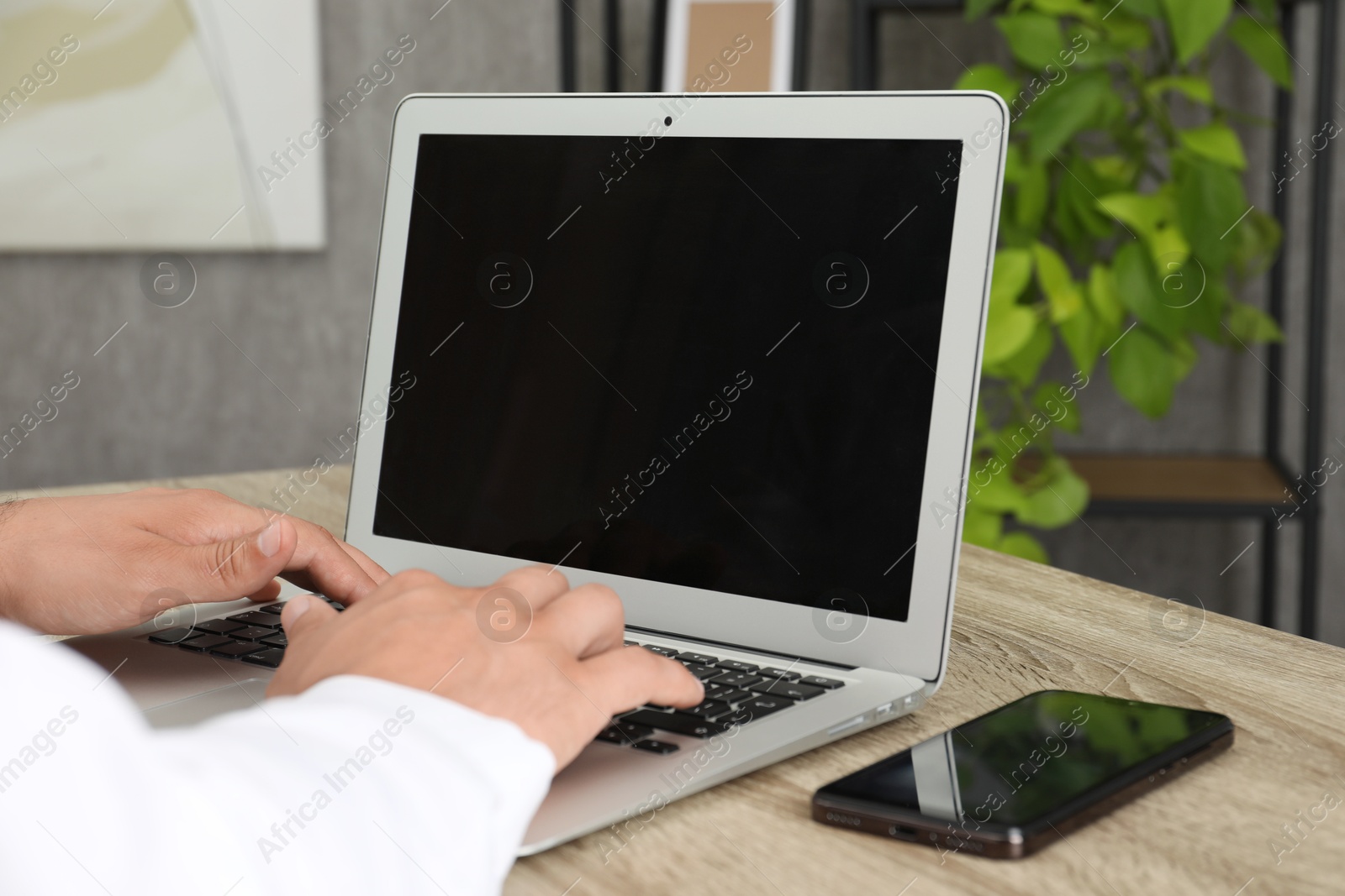 Photo of Businessman using laptop at wooden table, closeup. Modern technology