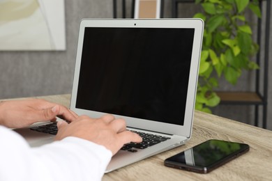 Photo of Businessman using laptop at wooden table, closeup. Modern technology