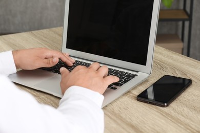 Photo of Businessman using laptop at wooden table, closeup. Modern technology