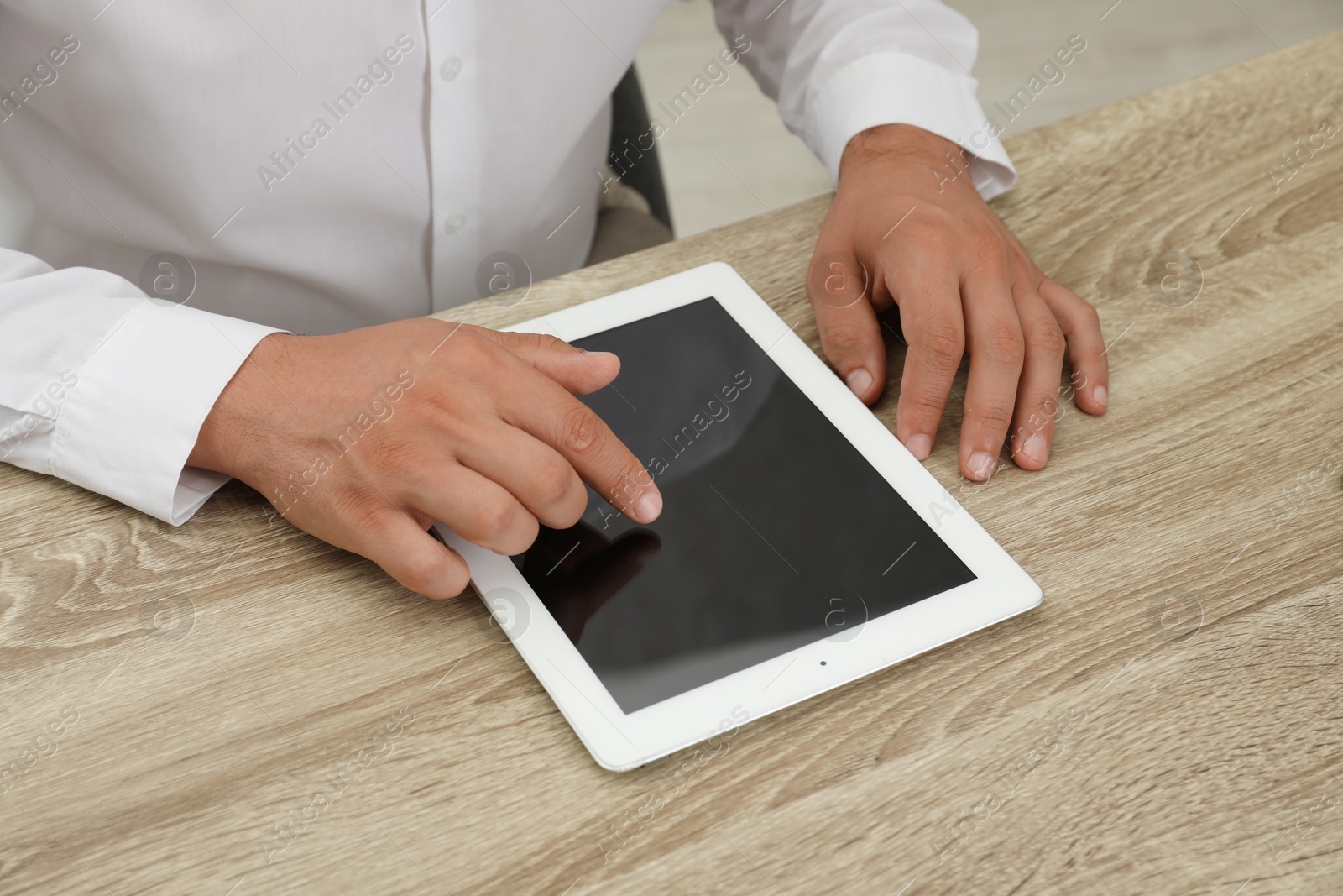 Photo of Businessman using tablet at wooden table, closeup. Modern technology