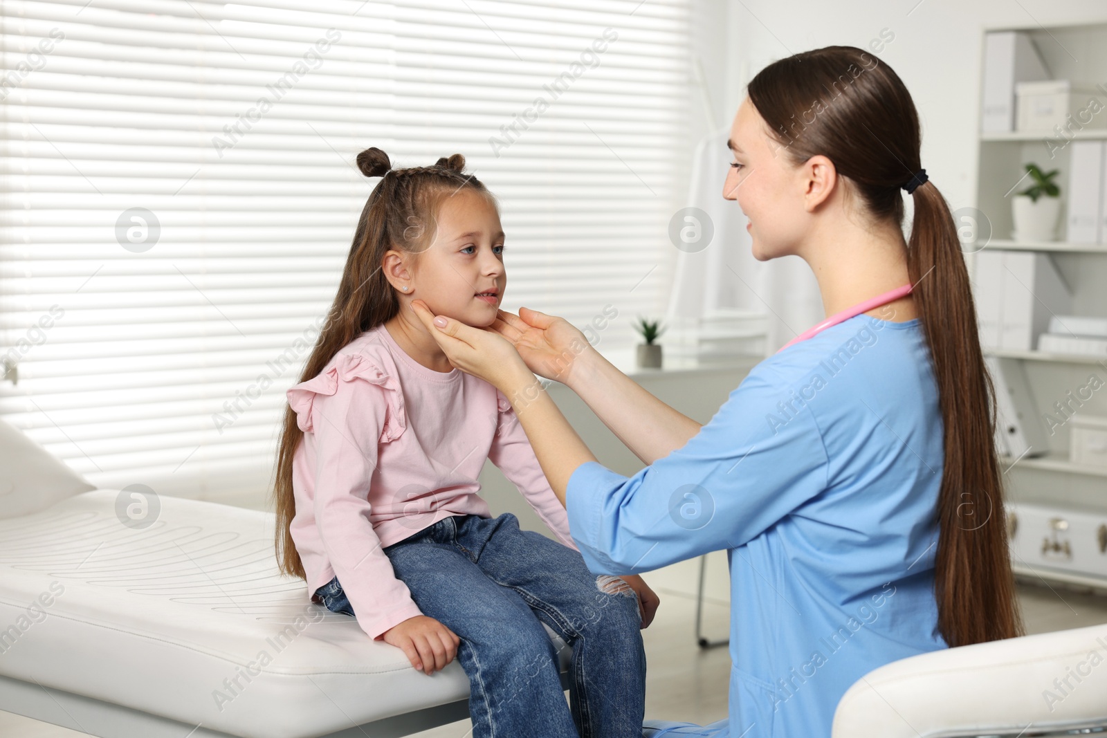 Photo of Doctor examining girl's throat in clinic during appointment