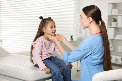 Photo of Doctor examining girl's throat in clinic during appointment