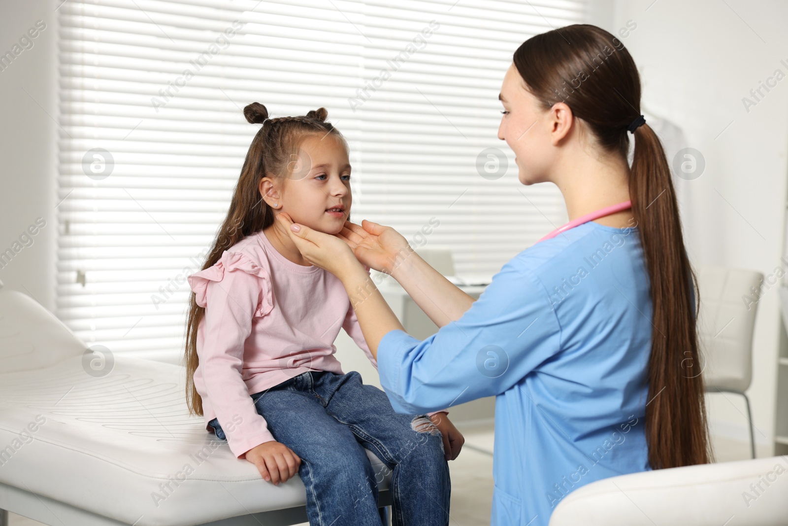 Photo of Doctor examining girl's throat in clinic during appointment