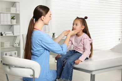 Photo of Doctor examining girl's throat in clinic during appointment