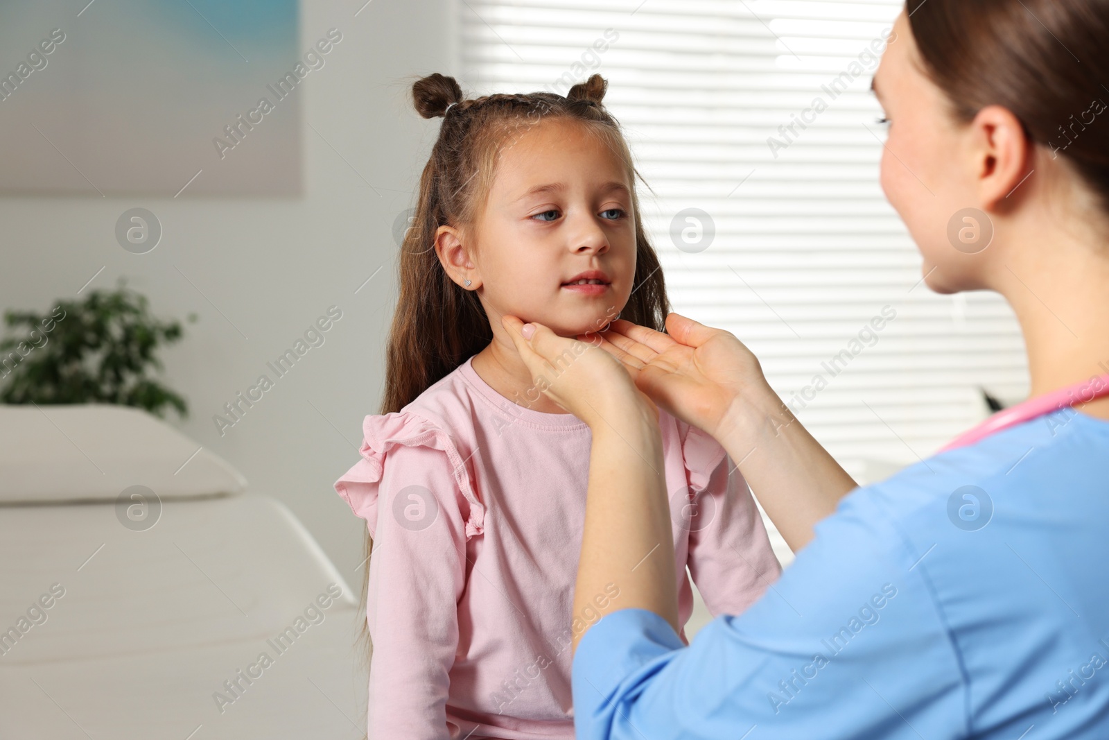 Photo of Doctor examining girl's throat in clinic during appointment