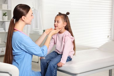 Photo of Doctor examining girl's throat in clinic during appointment