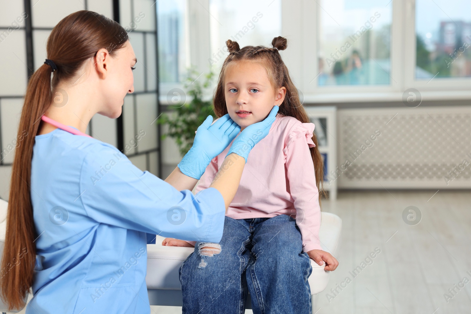 Photo of Doctor examining girl's throat in clinic during appointment