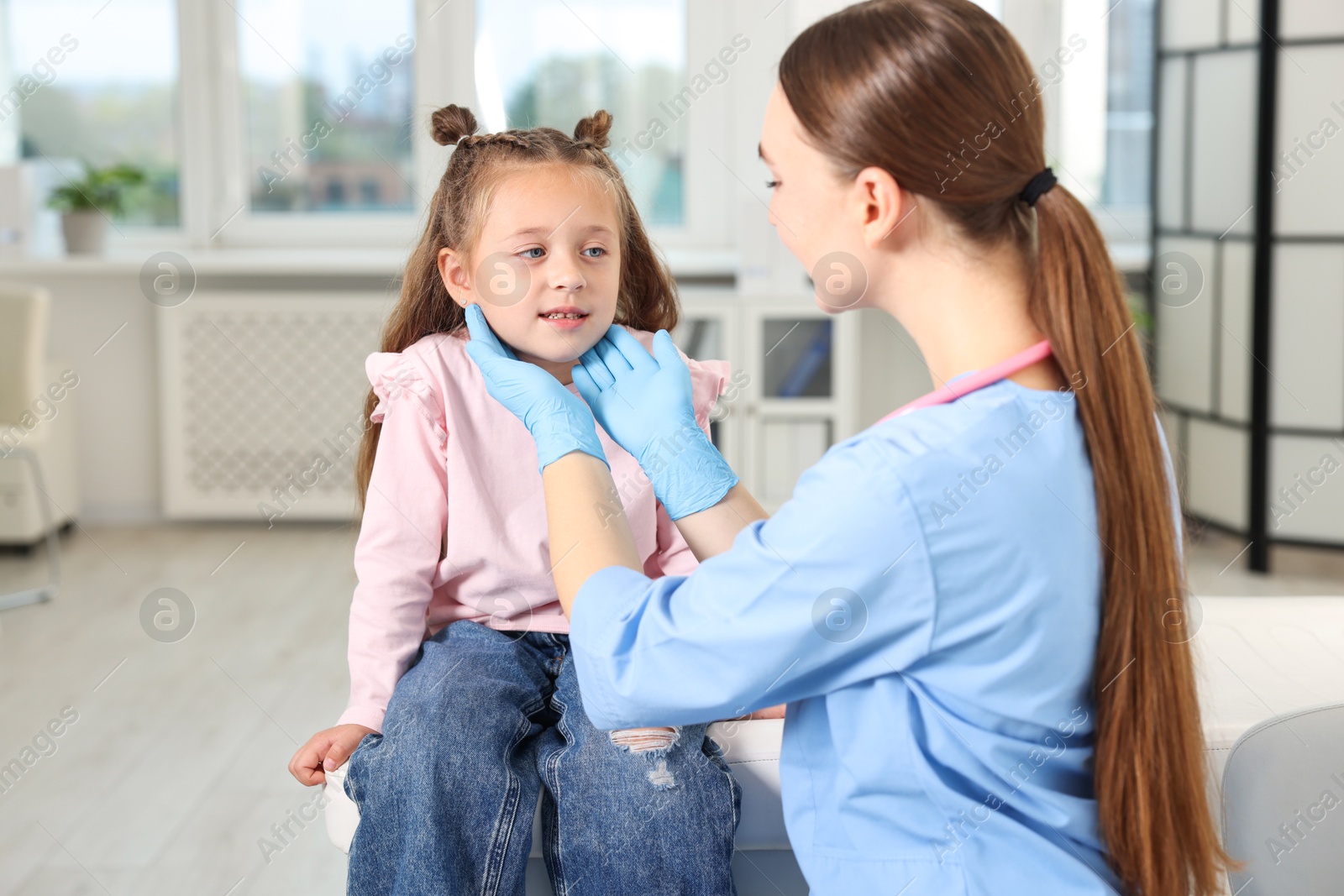 Photo of Doctor examining girl's throat in clinic during appointment