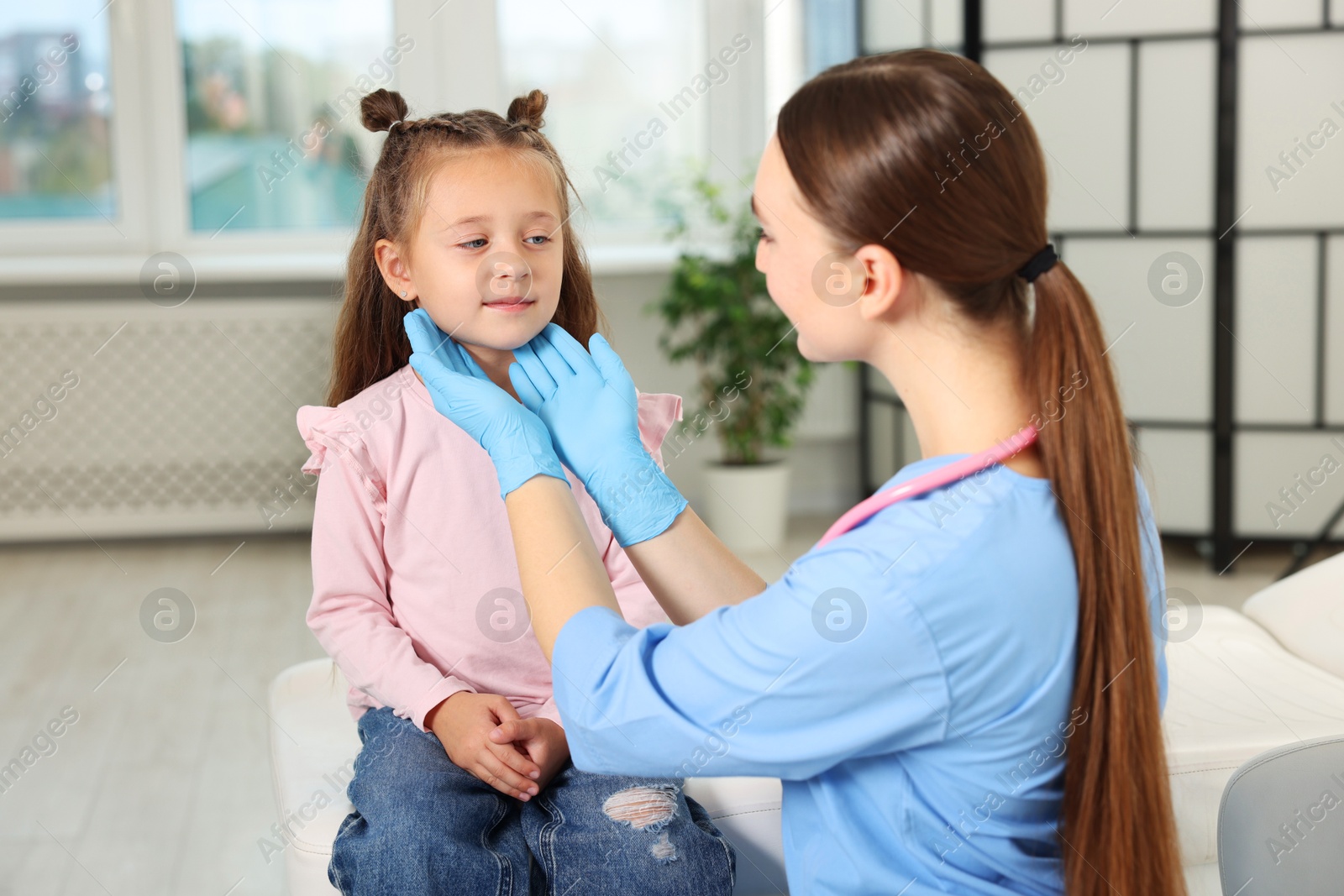 Photo of Doctor examining girl's throat in clinic during appointment