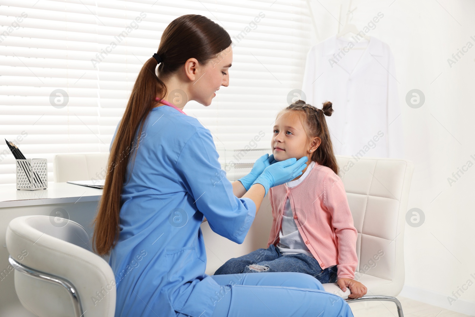 Photo of Doctor examining girl's throat in clinic during appointment