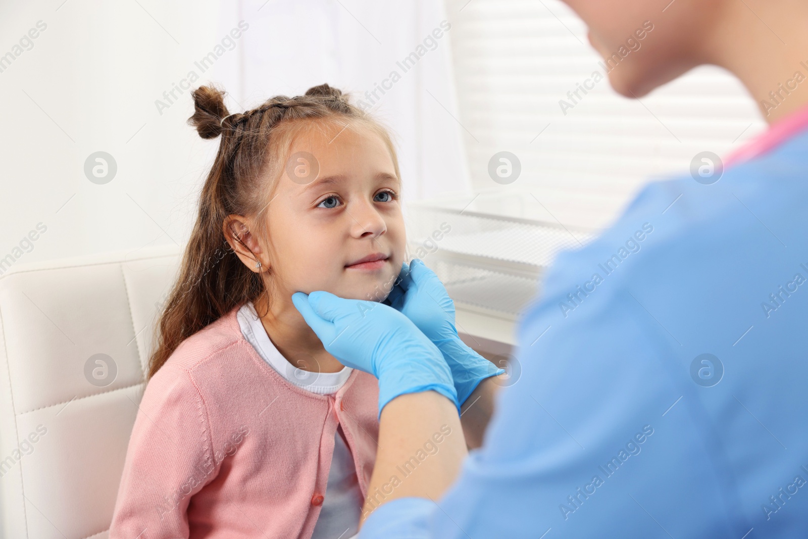 Photo of Doctor examining girl's throat in clinic during appointment