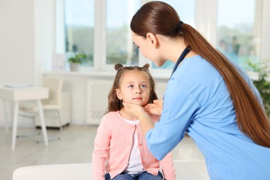 Photo of Doctor examining girl's throat in clinic during appointment