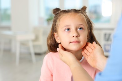 Photo of Doctor examining girl's throat in clinic during appointment