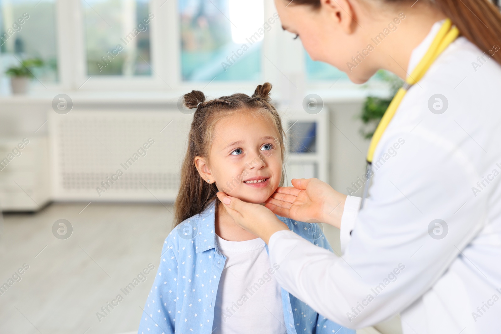 Photo of Doctor examining girl's throat in clinic during appointment