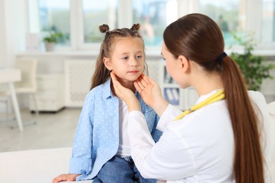 Photo of Doctor examining girl's throat in clinic during appointment