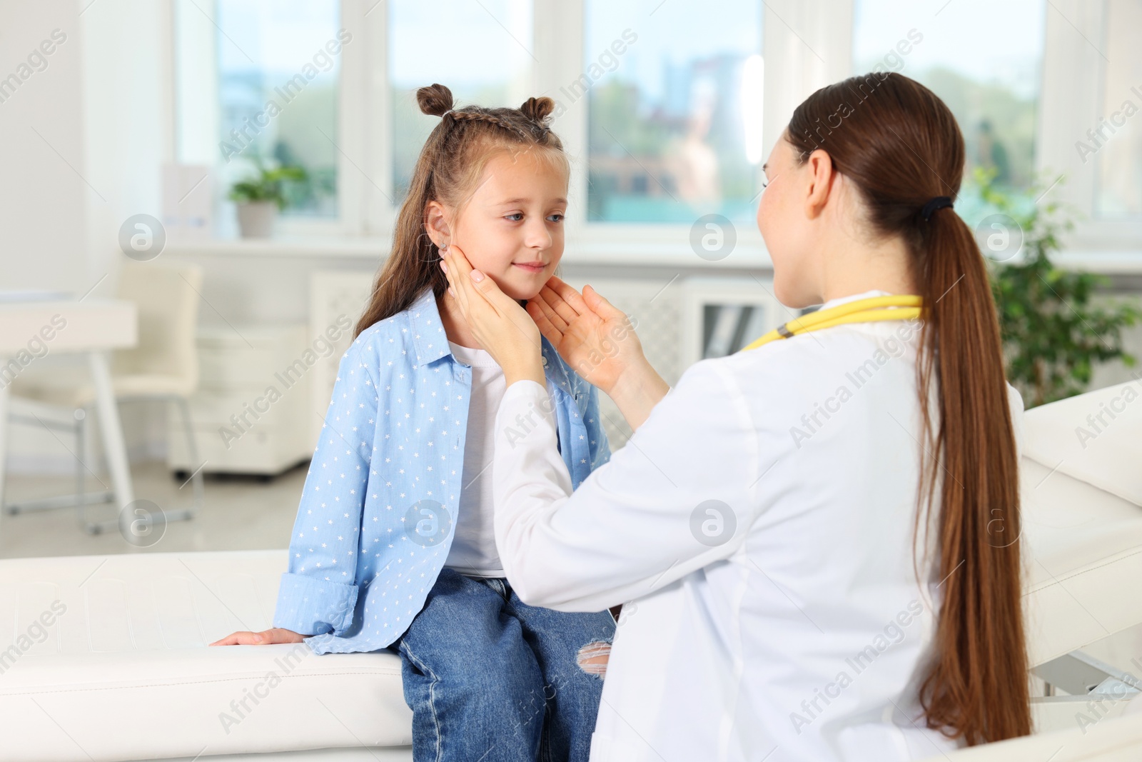 Photo of Doctor examining girl's throat in clinic during appointment