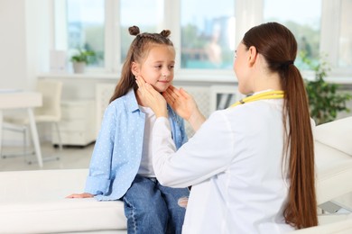 Photo of Doctor examining girl's throat in clinic during appointment