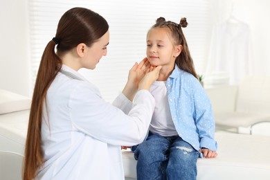 Photo of Doctor examining girl's throat in clinic during appointment